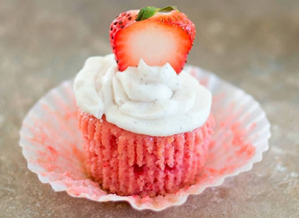 Strawberry cupcake sitting on wrapper.