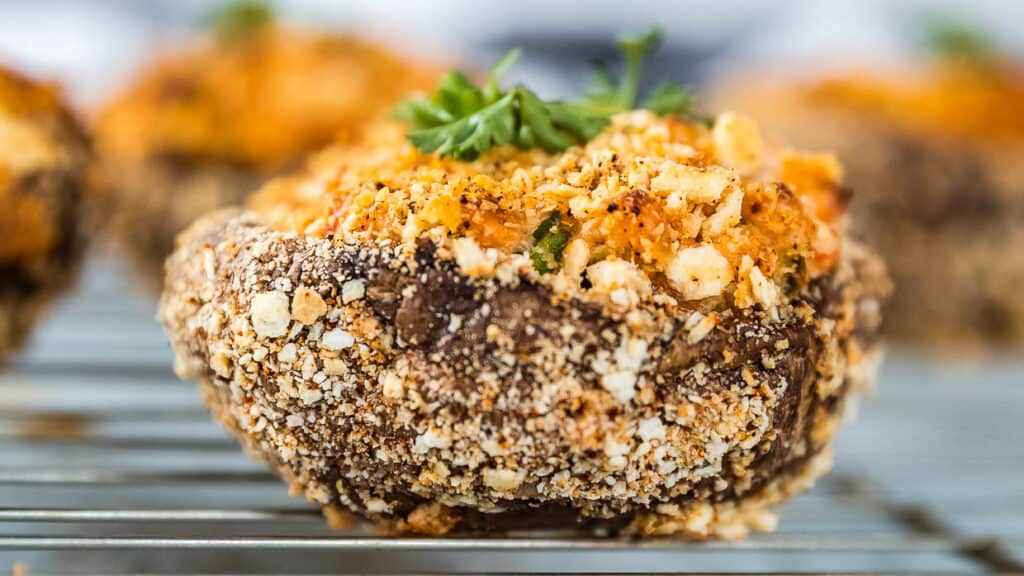 Stuffed Portobello Mushrooms on a wire rack with parsley and breadcrumbs.