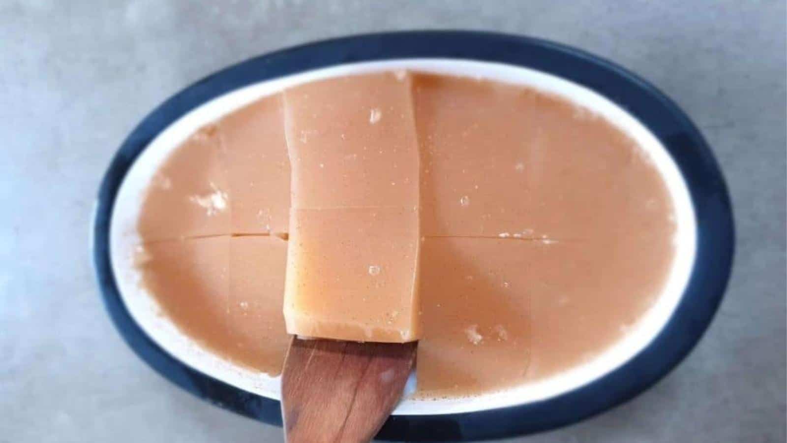 Sugar-free gelatin in an oval bowl cut with wooden spatula.