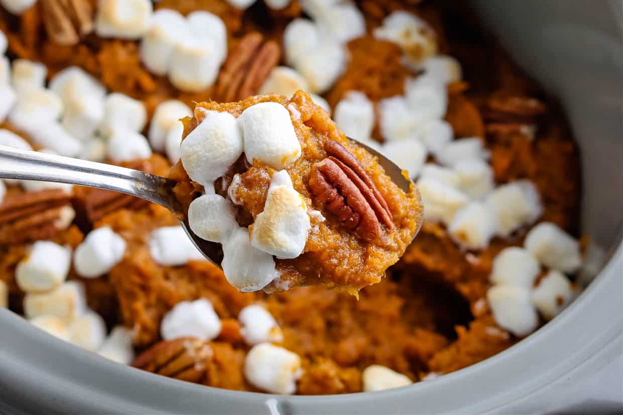 Crock pot with sweet potato casserole with pecans and marshmallows.