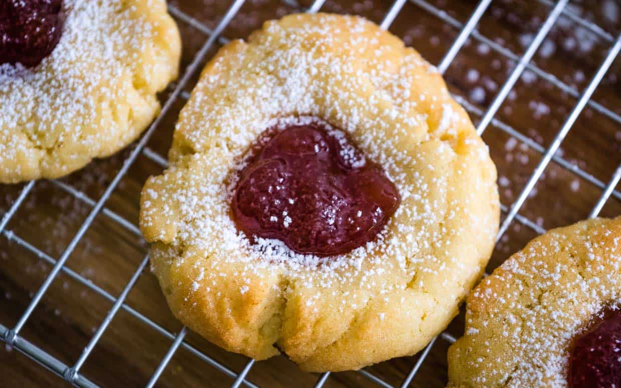 Top view of thumbprint cookie with strawberry jam and sprinkled with powdered sugar.