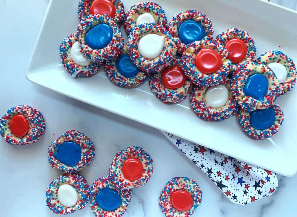 Red, white and blue sprinkled thumbprint cookies with icing.