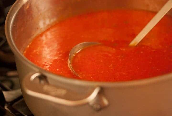 A pot of tomato soup with a ladle.