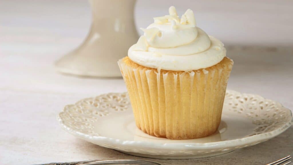 Vanilla cupcake with frosting on white china plate