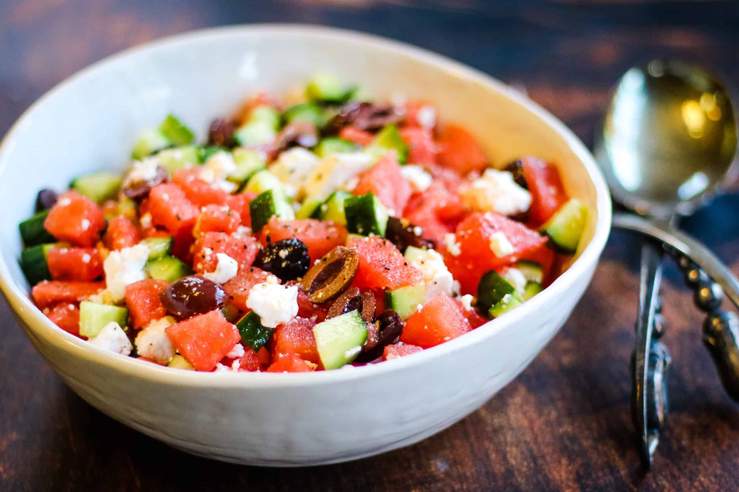 Low angle shot of a bowl of watermelon salad with kalamata olives and feta cheese.