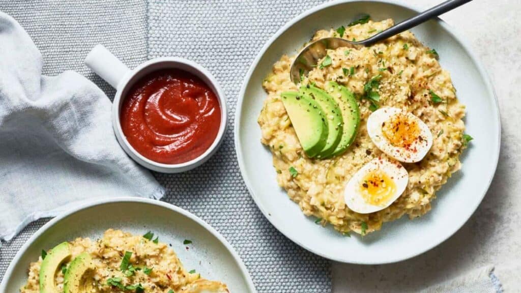 Ceramic bowls filled with oatmeal garnished with eggs and avocado.