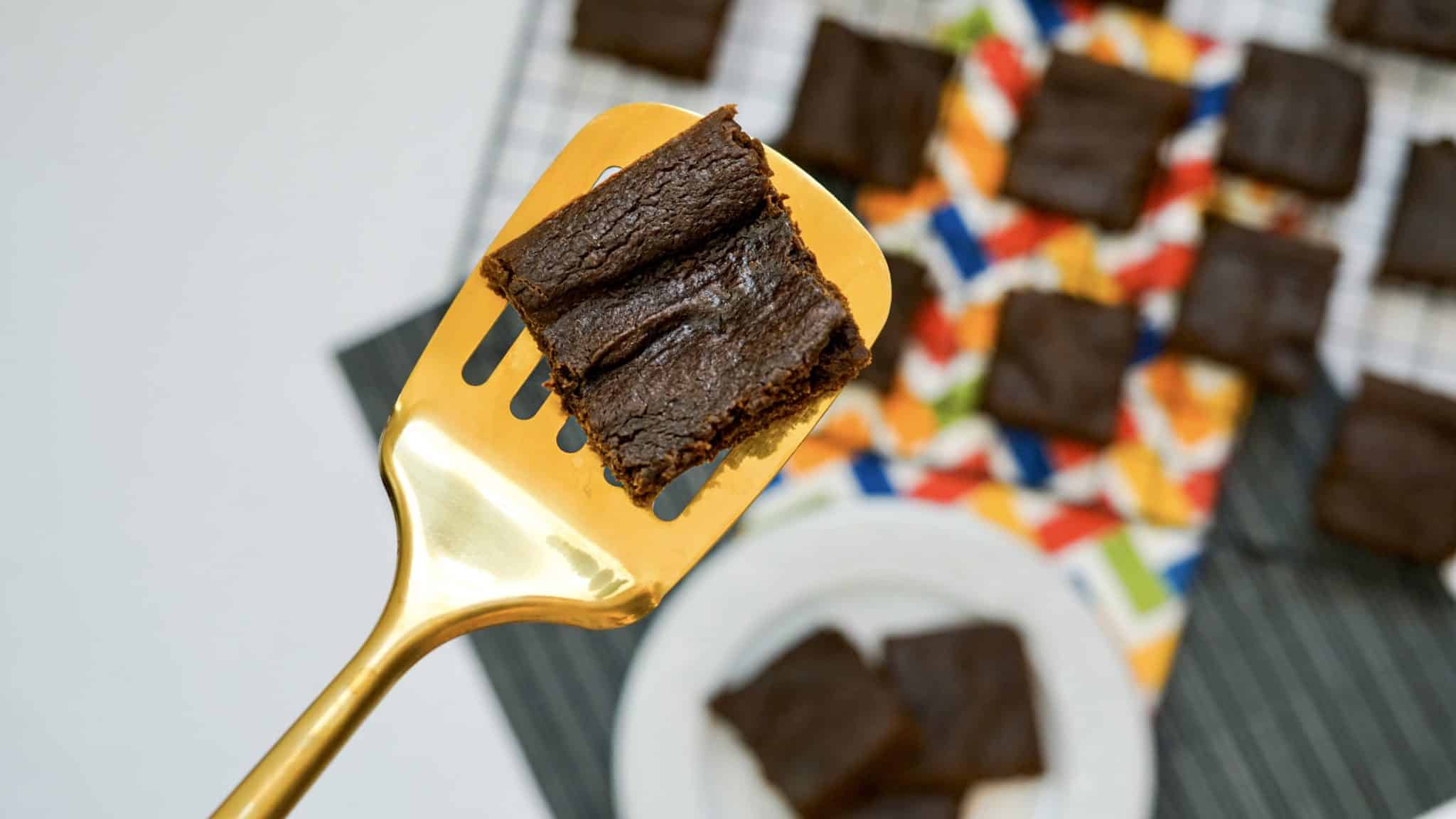 A chocolate brownie on a gold spatula.