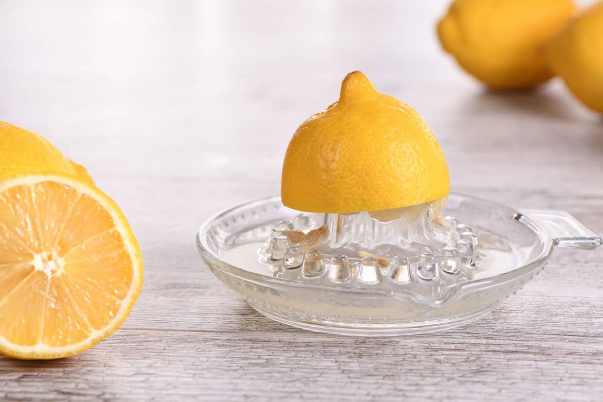 A picture of a cut lemon on a glass lemon juicer.