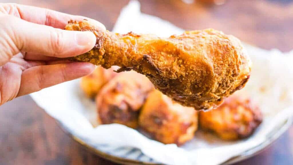 Hand holding a fried chicken drumstick.