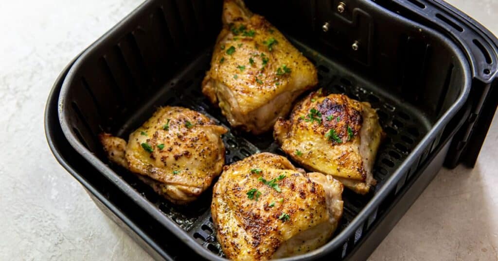 Lemon pepper chicken thighs in an air fryer basket