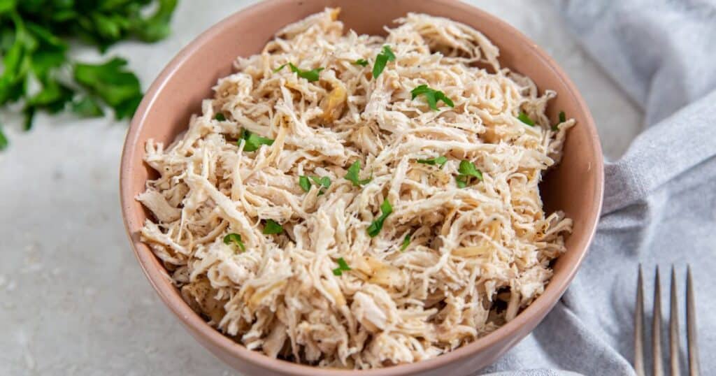 Air Fryer Shredded Chicken in a pink bowl topped with parsley.