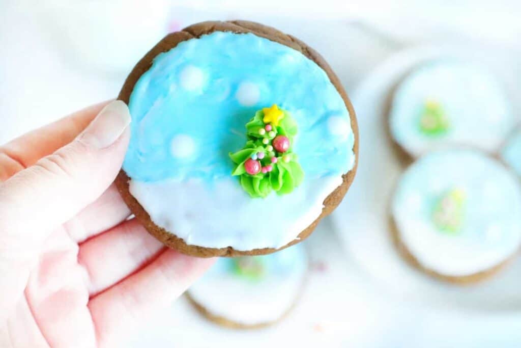A hand holding a blue and white frosted gungerbread cookie.