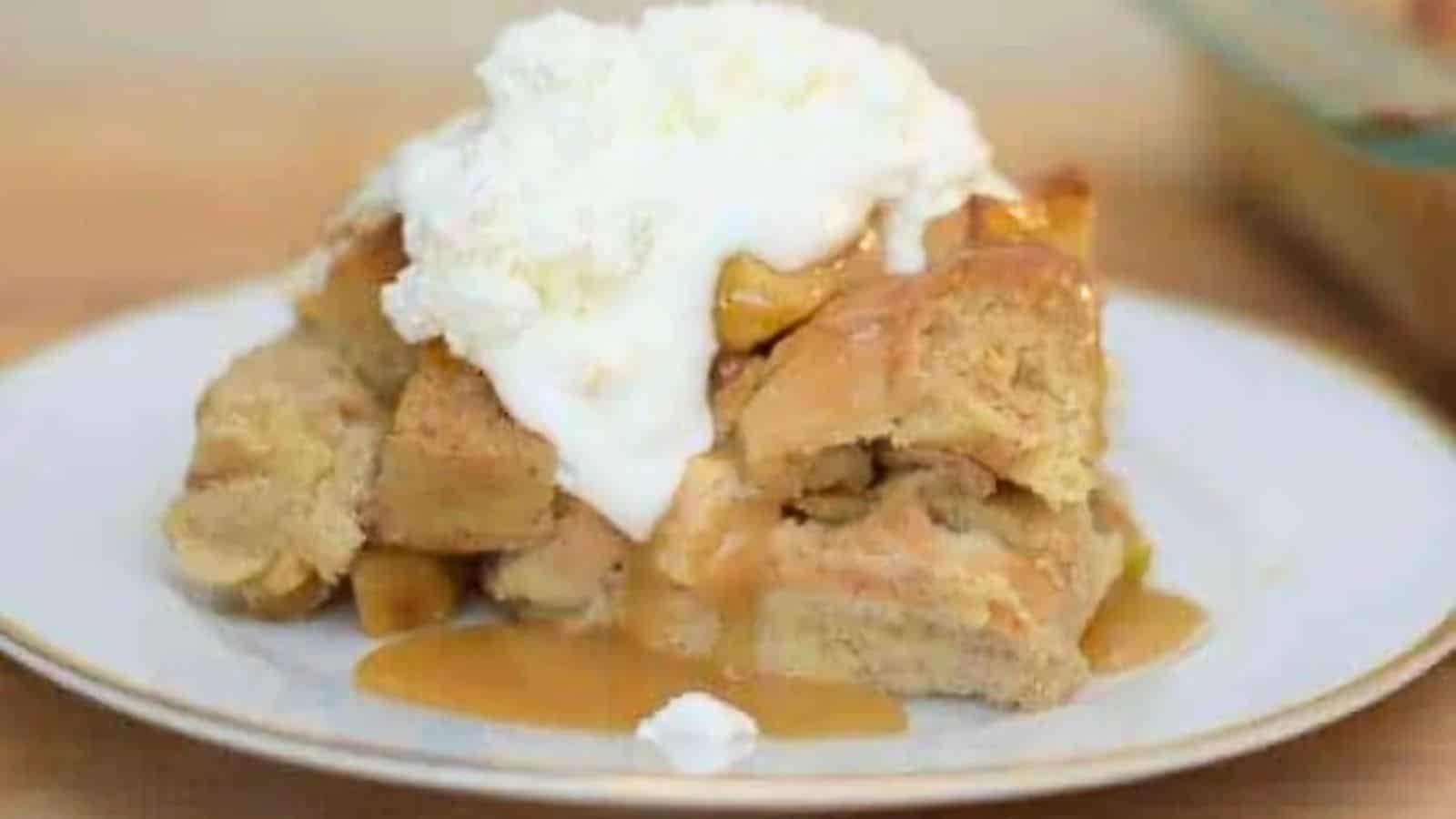 Image shows a head on close up shot of a slice of Apple Pie Bread Pudding topped with whipped cream.