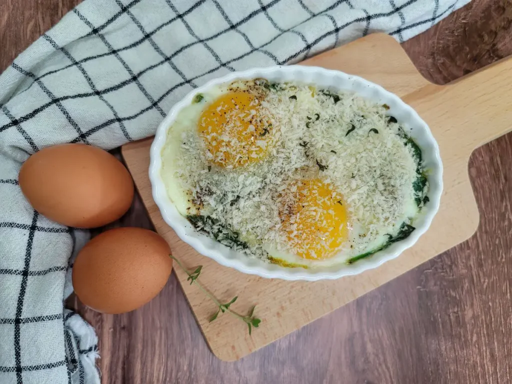 A gratin dish of baked eggs on a bed of sauteed spinach.