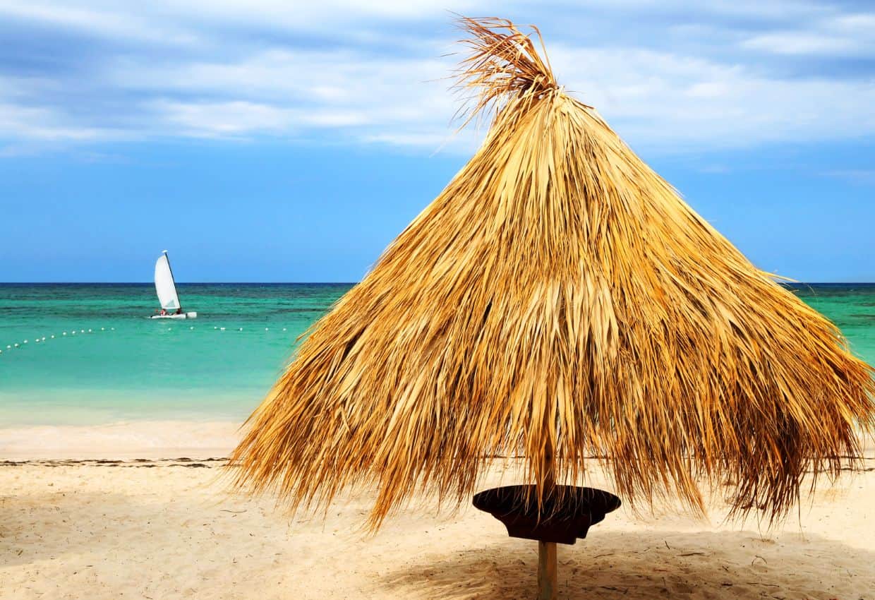 Beach facing the ocean in Punta Cana with a thatch shaded table.