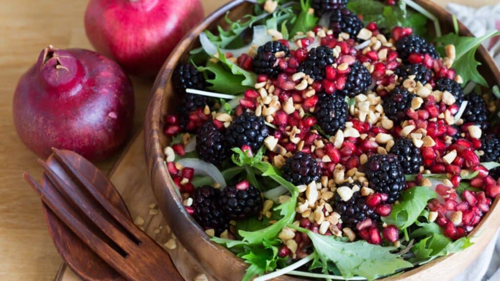 side view of berry salad in bowl with pomegranates.