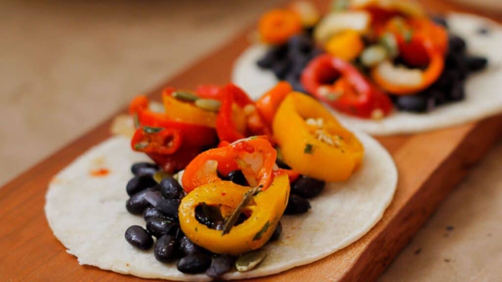 two black bean tacos on wooden board.