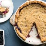 Overhead shot of blackberry crumble pie with one slice on a serving plate