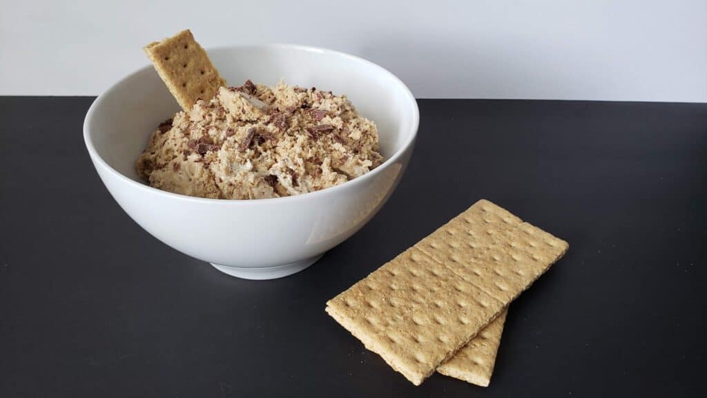 Image shows a Bowl of edible smores cookie dough with graham crackers around it.