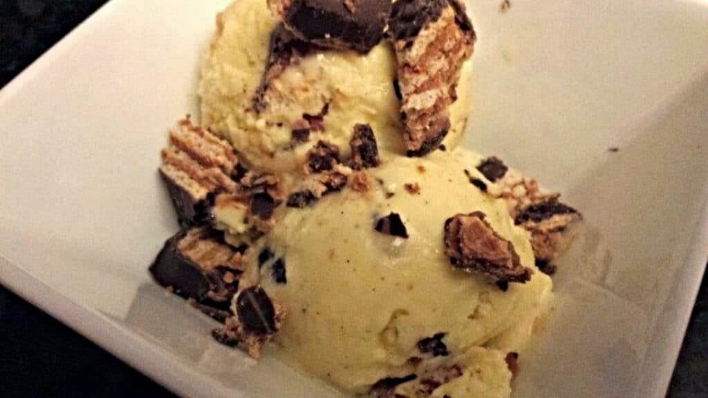 Bowl of salted caramel ice cream with chopped candy on it.