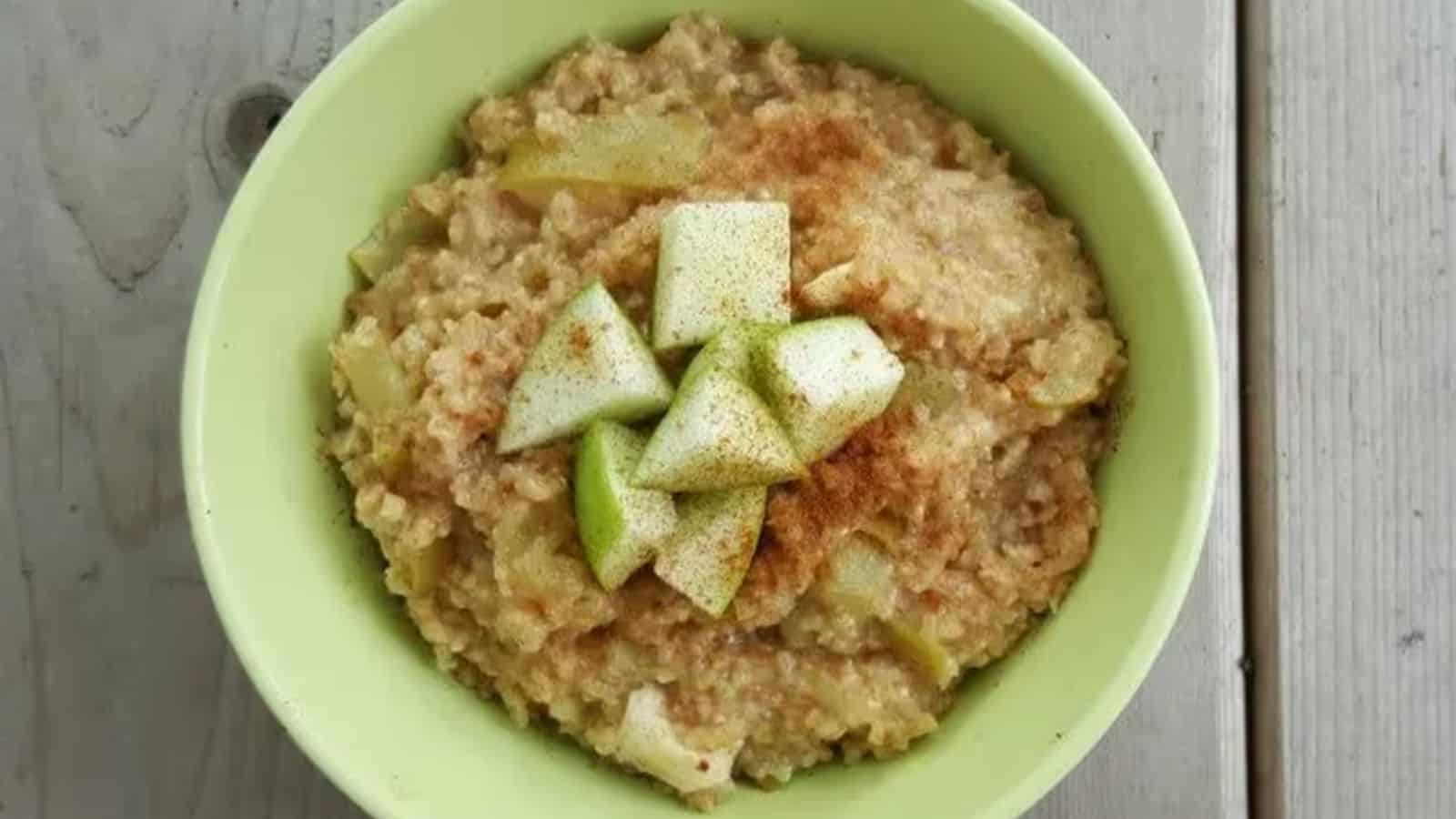 Image shows Caramelized Apple Oatmeal in a green bowl topped with chopped apples and cinnamon.