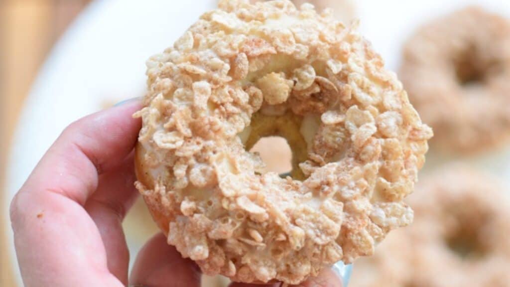 Image shows a Cereal topped donut held over more.