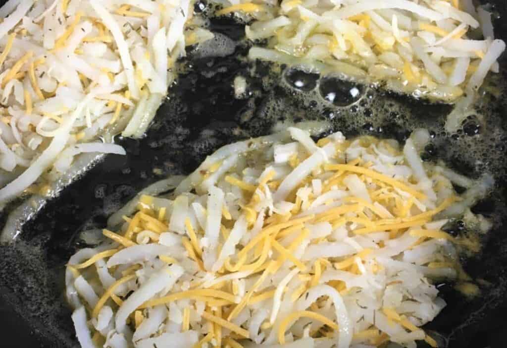 Cheesy hash browns cooking in skillet