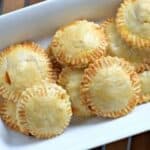 Image shows an overhead shot of puff pastry Chicken Empanadas on a white tray.