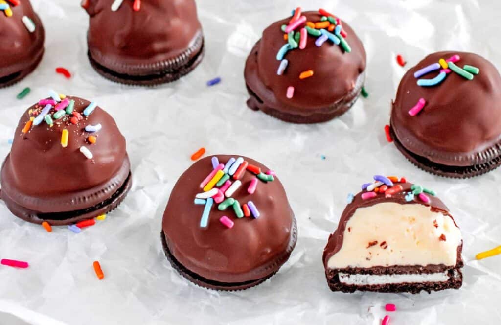Chocolate covered ice cream bites on a piece of parchment paper.