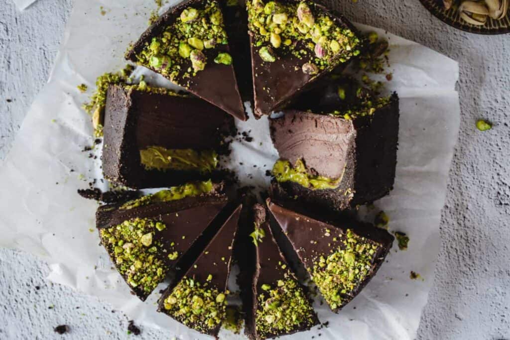 Image shows an overhead shot of chocolate pistachio cake in slices.