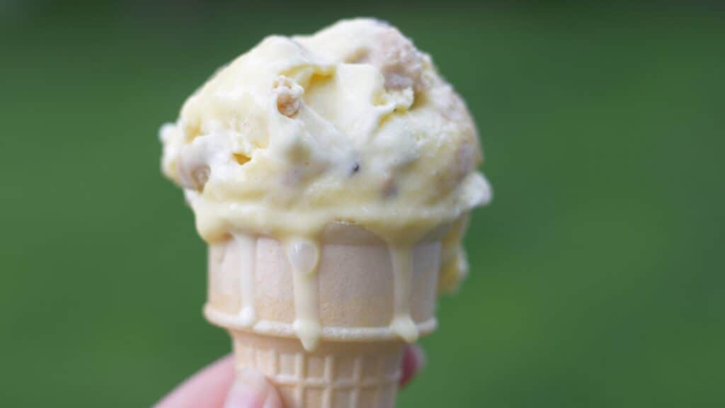Cookie dough frozen custard on a cone with drips.