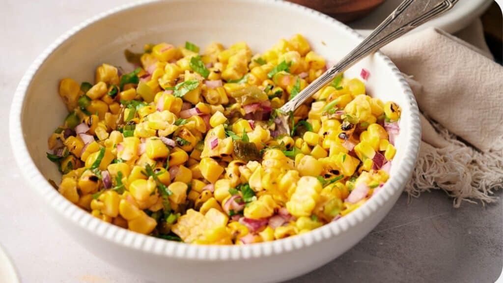 A bowl of freshly made Copycat Chipotle corn salsa with a serving spoon in it.