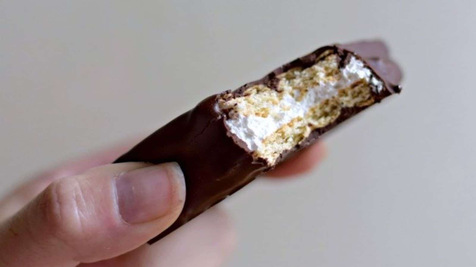 Image shows a hand holding a copycat Girl Scout s'mores cookie with a bite taken from it.