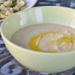 Image shows a bowl of Creamy Tuscan Bean Soup with a drizzle of olive oil in a green bowl.