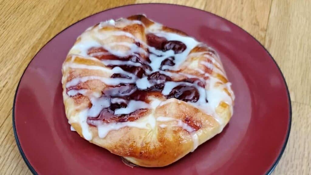 Image shows a Crescent Roll Danish on a red plate.
