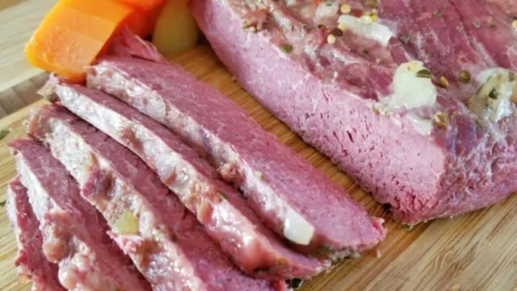 Image shows an overhead close up shot of Crockpot Corned Beef partially sliced and partially the whole roast.