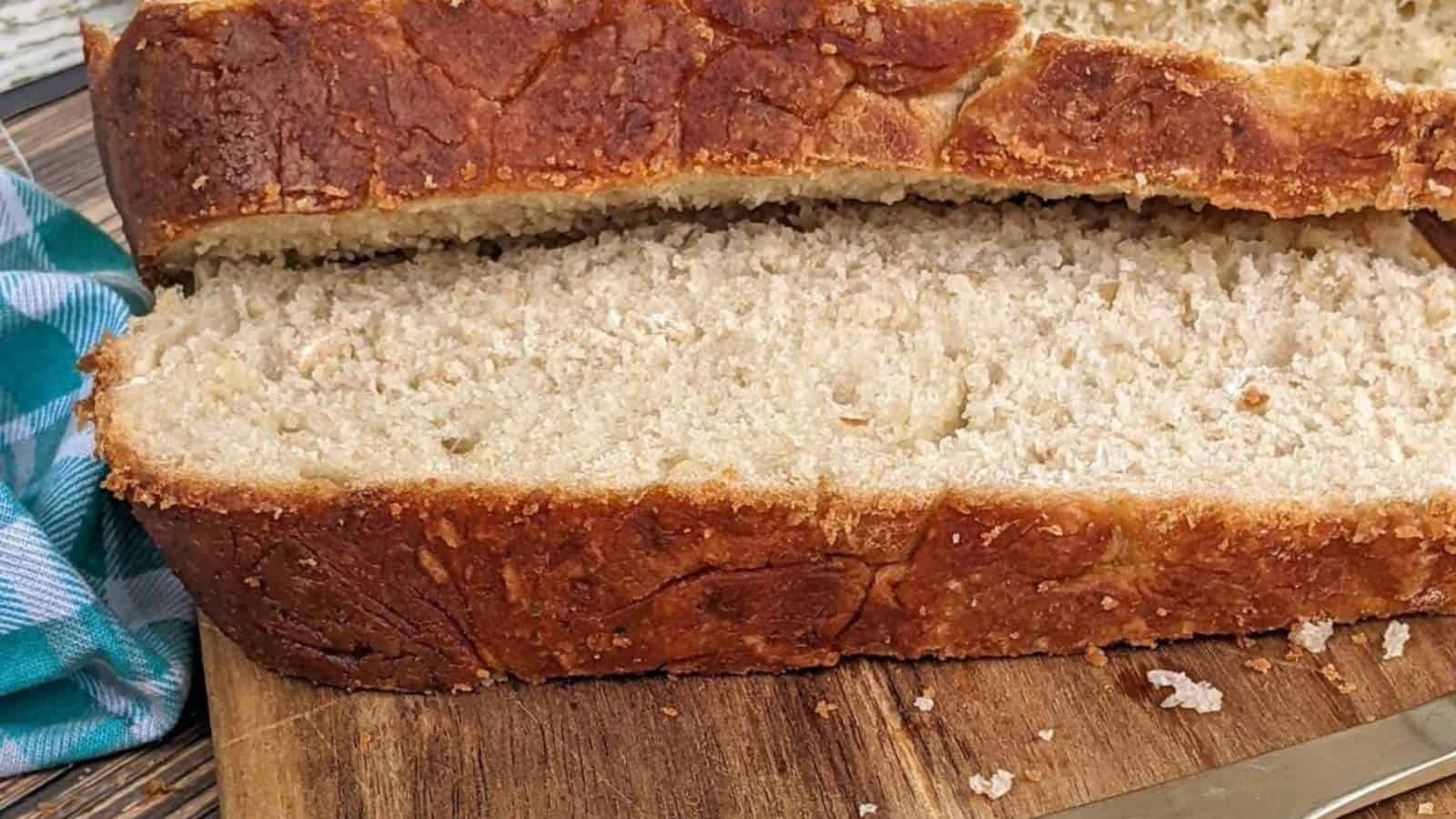 Dutch oven artisan bread slice on wooden cutting board.