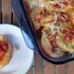 Image shows an overhead shot of Easy Cheesy Stuffed Shells with a small plate holding one and the rest of the pan next to it.