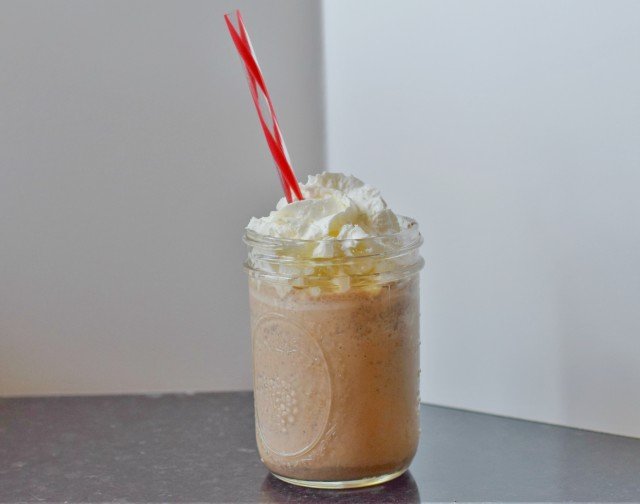 Image shows a mason jar with a java chip frappuccino topped with whipped cream.