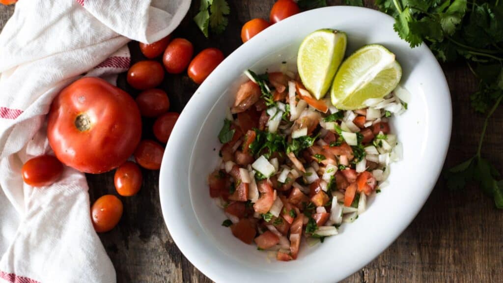 overhead of pico de gallo in white bowl with veggies around.