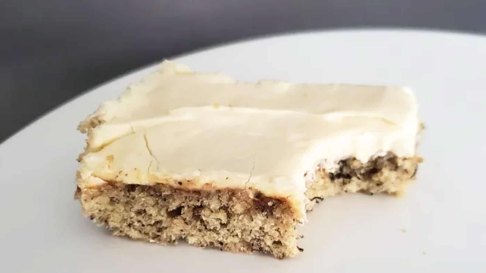 Image shows a Frosted Banana Bar with a bite taken from it on a white plate.