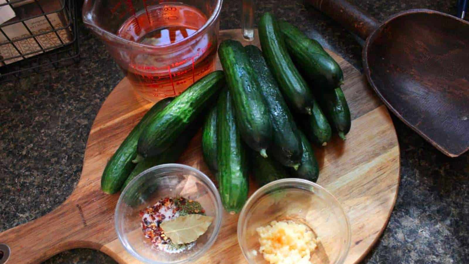Ingedients for garlic dill pickles on a wooden cutting board.