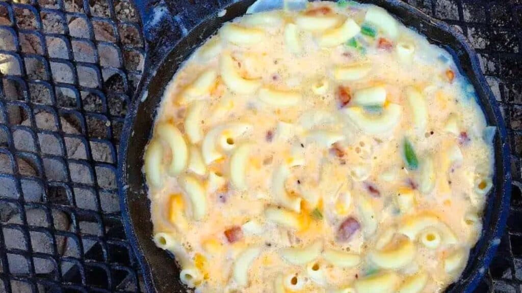 A skillet of mac and cheese over a campfire.