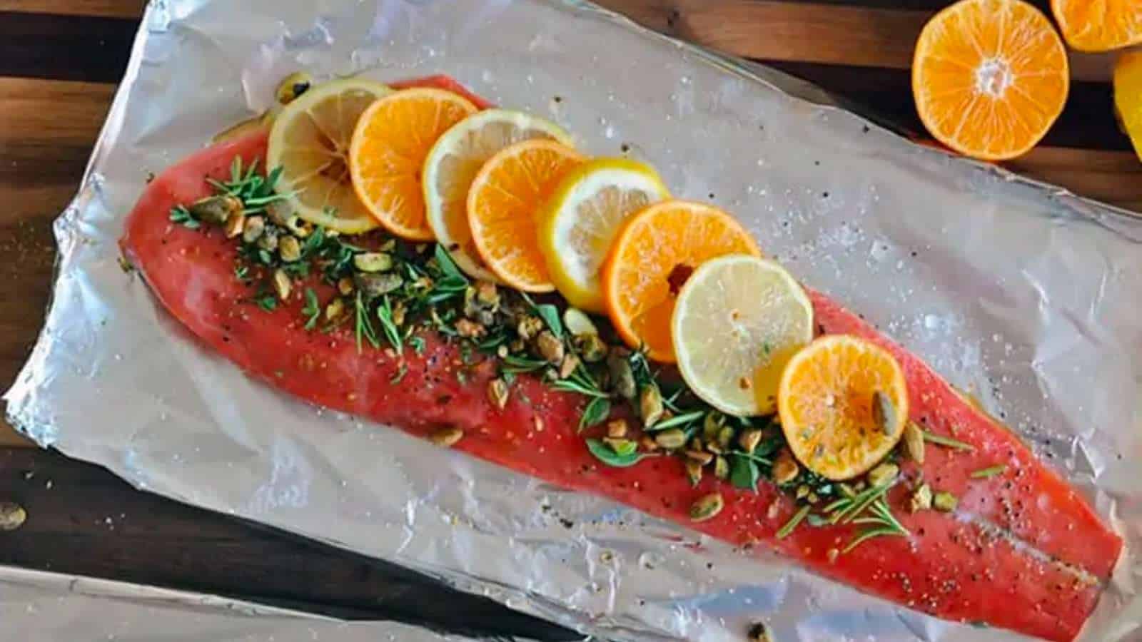 Salmon on foil with nuts and citrus on top.