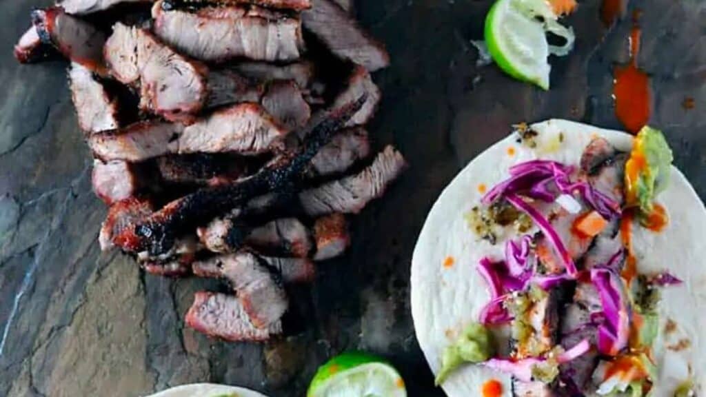 Platter of sliced pork steaks with tacos.