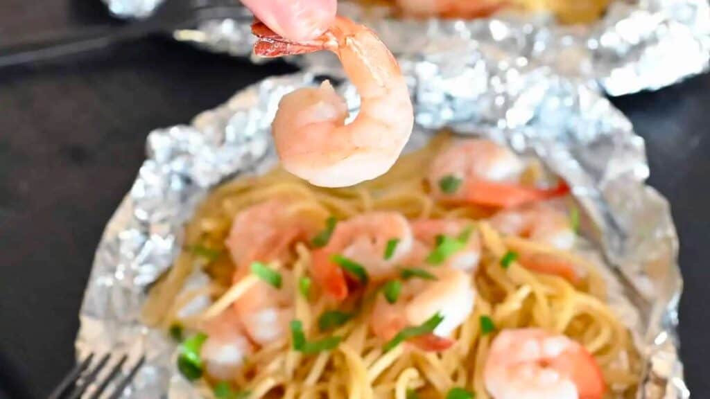 Pulling out a shrimp from shrimp scampi foil packet.