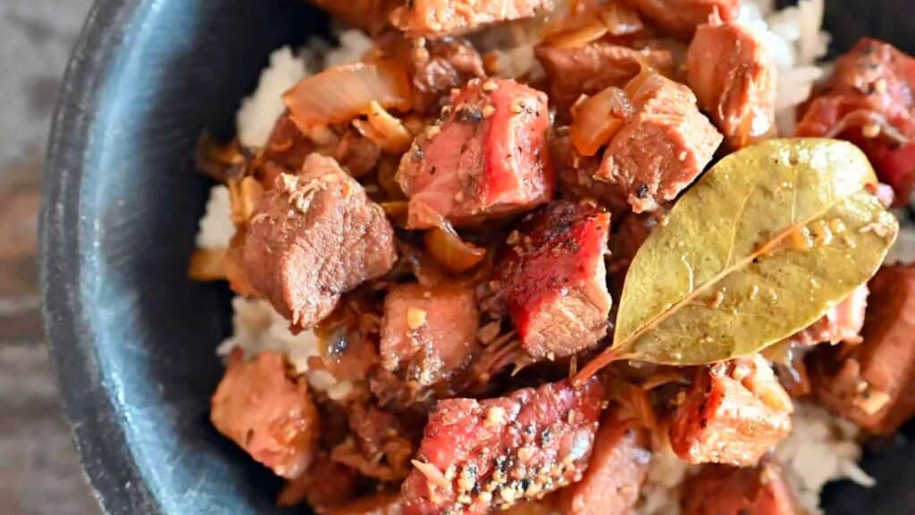 Bowl of pork adobo with bay leaf on top.