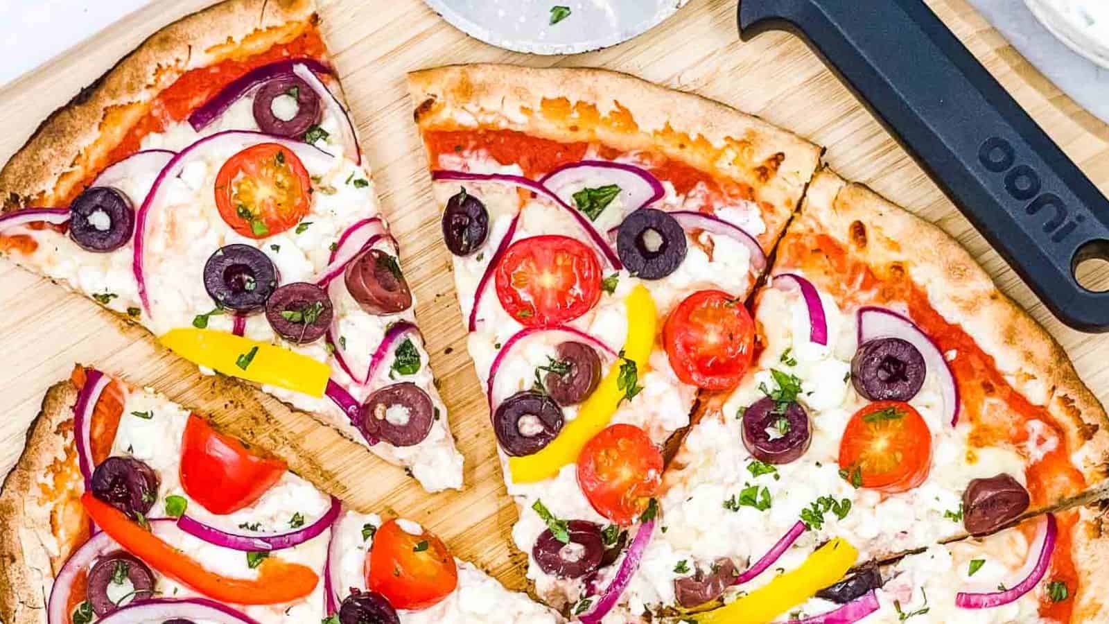 Greek pizza, sliced on a board.