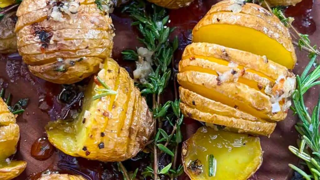 Plate of grilled mini hasselback potatoes with rosemary.