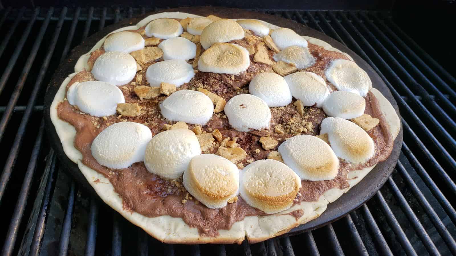 Image shows a grilled s'mores pizza on the grill.